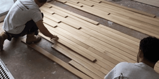 Professionals installing a hardwood floor.