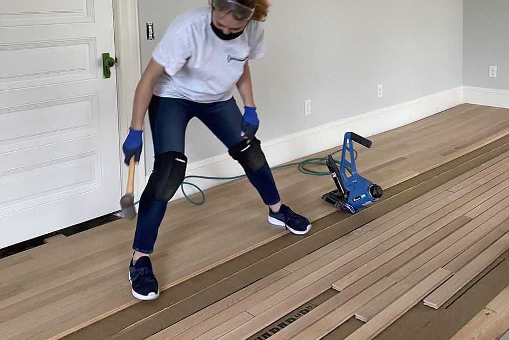 Expert wood floor installer carefully laying out boards.