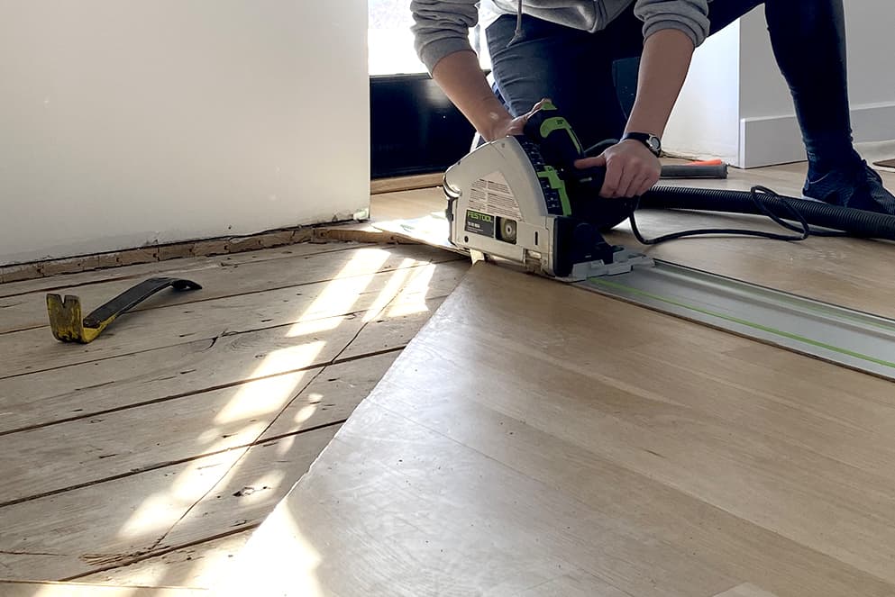 Skilled flooring specialist cutting a damaged area of floor to repair and restore.